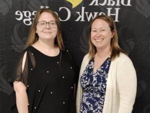 2 people standing in front of Black Hawk College banner